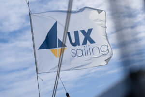 Bandera ondeando al viento con la inscripción 'UX Sailing'