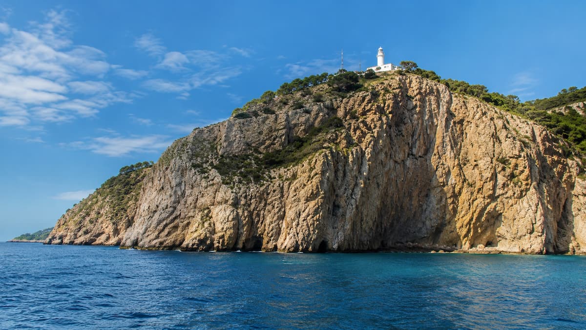 Vista desde el mar del Cabo de la Nao, con el faro sobre los acantilados y el Mediterráneo en primer plano.